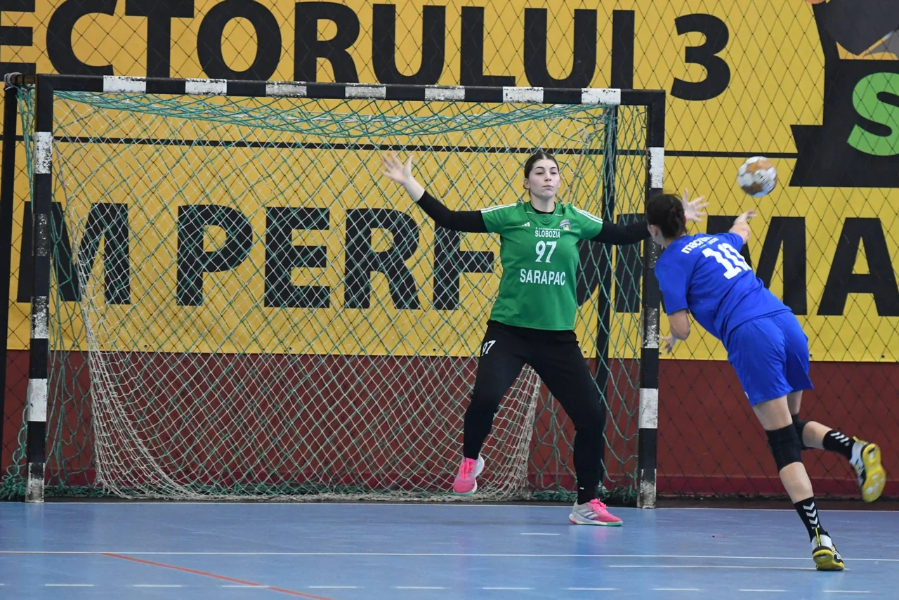 Portarul CSM Unirea, în verde, încearcă să oprească o aruncare de la extremă a unei jucătoare de la Spartac.
