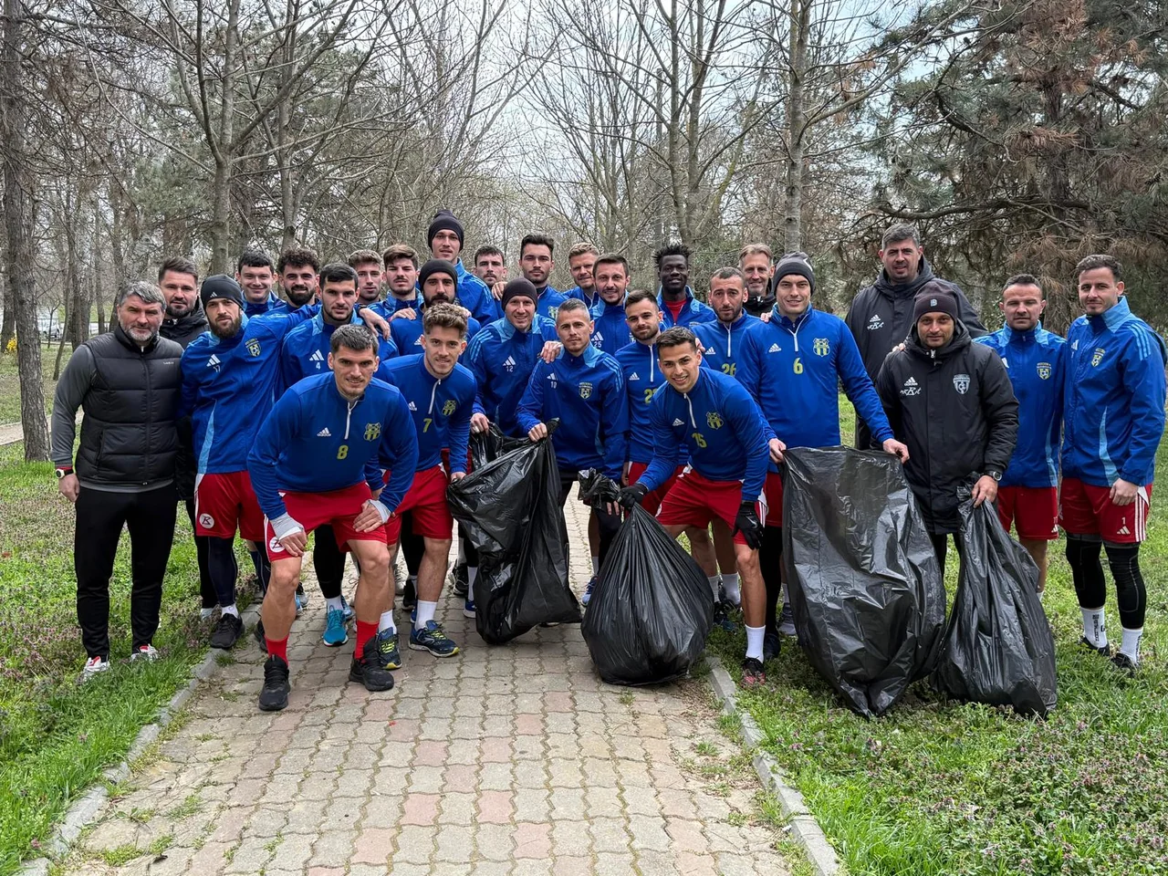 Lotul Unirea Slobozia și staff-ul pozează pe o alee din parc, lângă sacii plini cu gunoaie strânse.
