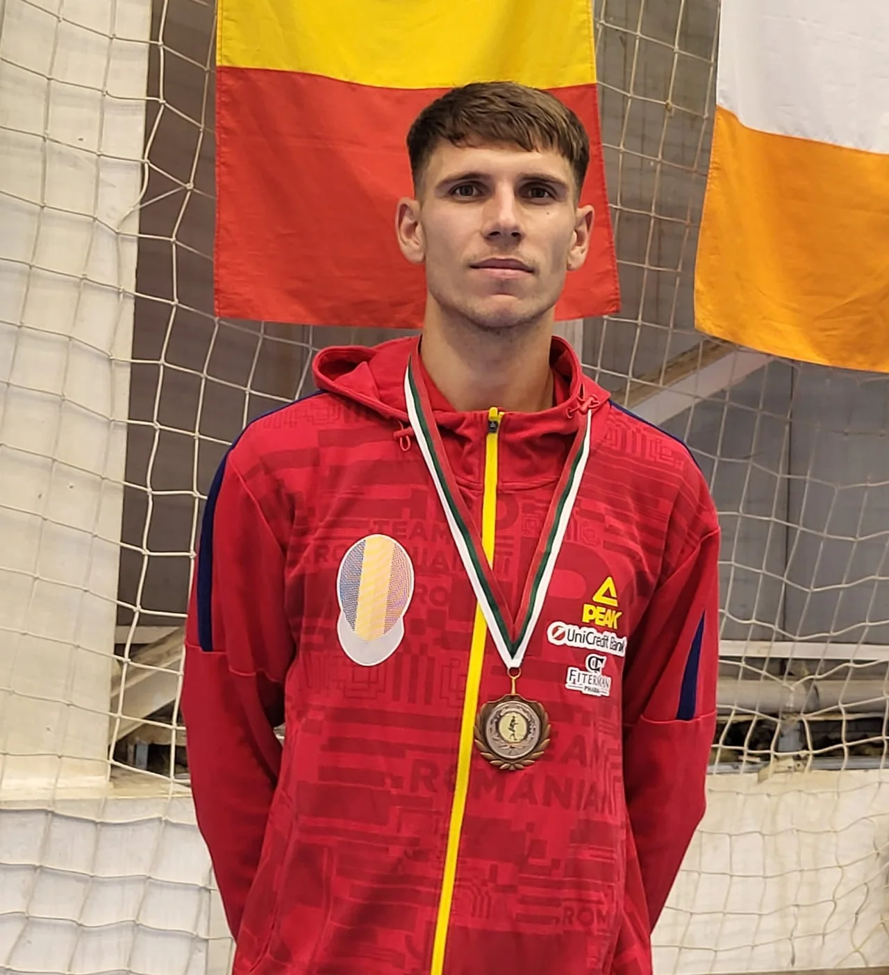 George Dragomir, în jacheta roșie a naționalei, poartă medalia de bronz câștigată la Campionatul Mondial de Scrimă.