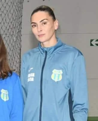 Cristina Gheorghe, antrenoare la secția de tenis, în geaca albastră a clubului, într-o sală de sport.