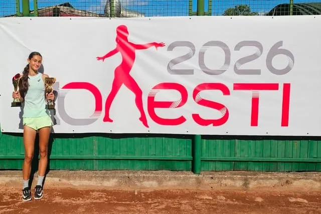 Irina Constantin ține cele două trofee câștigate la simplu și la dublu, în fața bannerului Onești 2026.