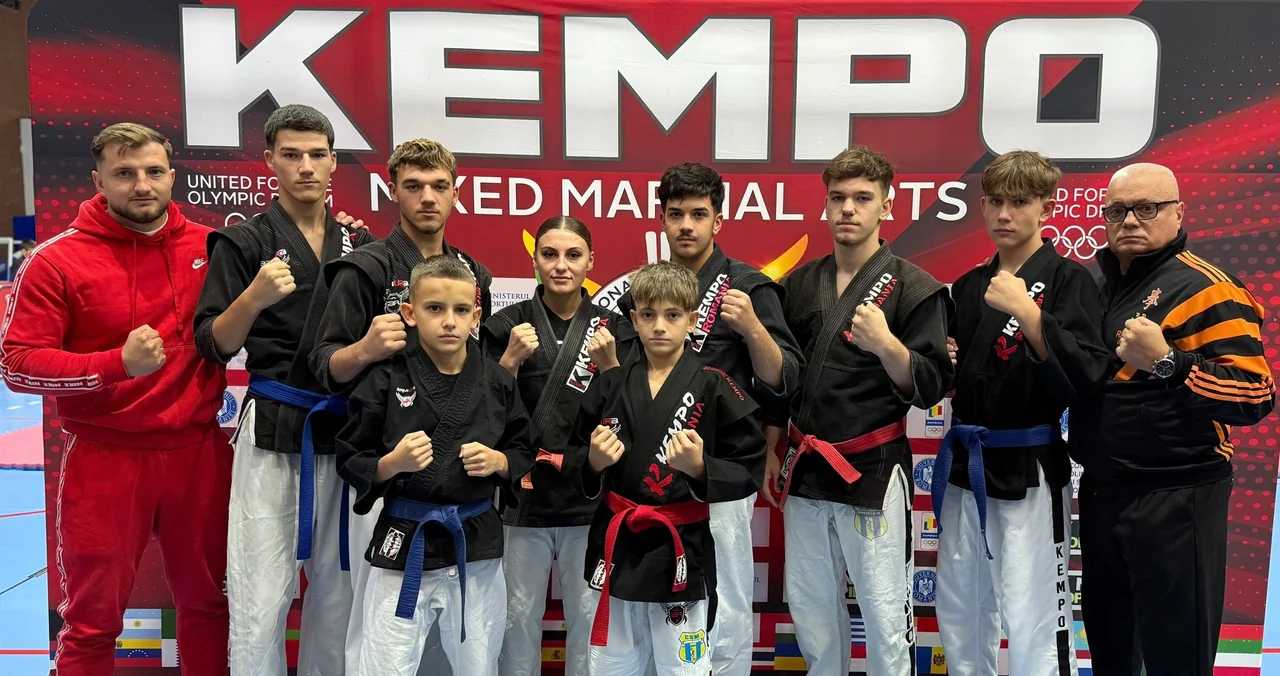 Echipa de kempo a clubului, în kimonouri negre, cu cei doi antrenori, în fața bannerului „Kempo Mixed Martial Arts”.