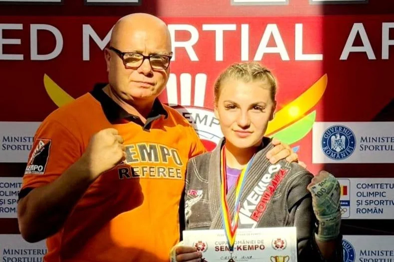 Irina Cîrstea, cu medalia și diploma Cupei României la Semi-Kempo, alături de un arbitru de kempo în tricou portocaliu.
