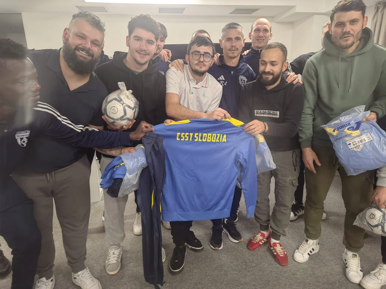 Suporteri și fotbaliști zâmbitori țin un trening cu inscripția „CSST Slobozia”, mingi și echipament nou.
