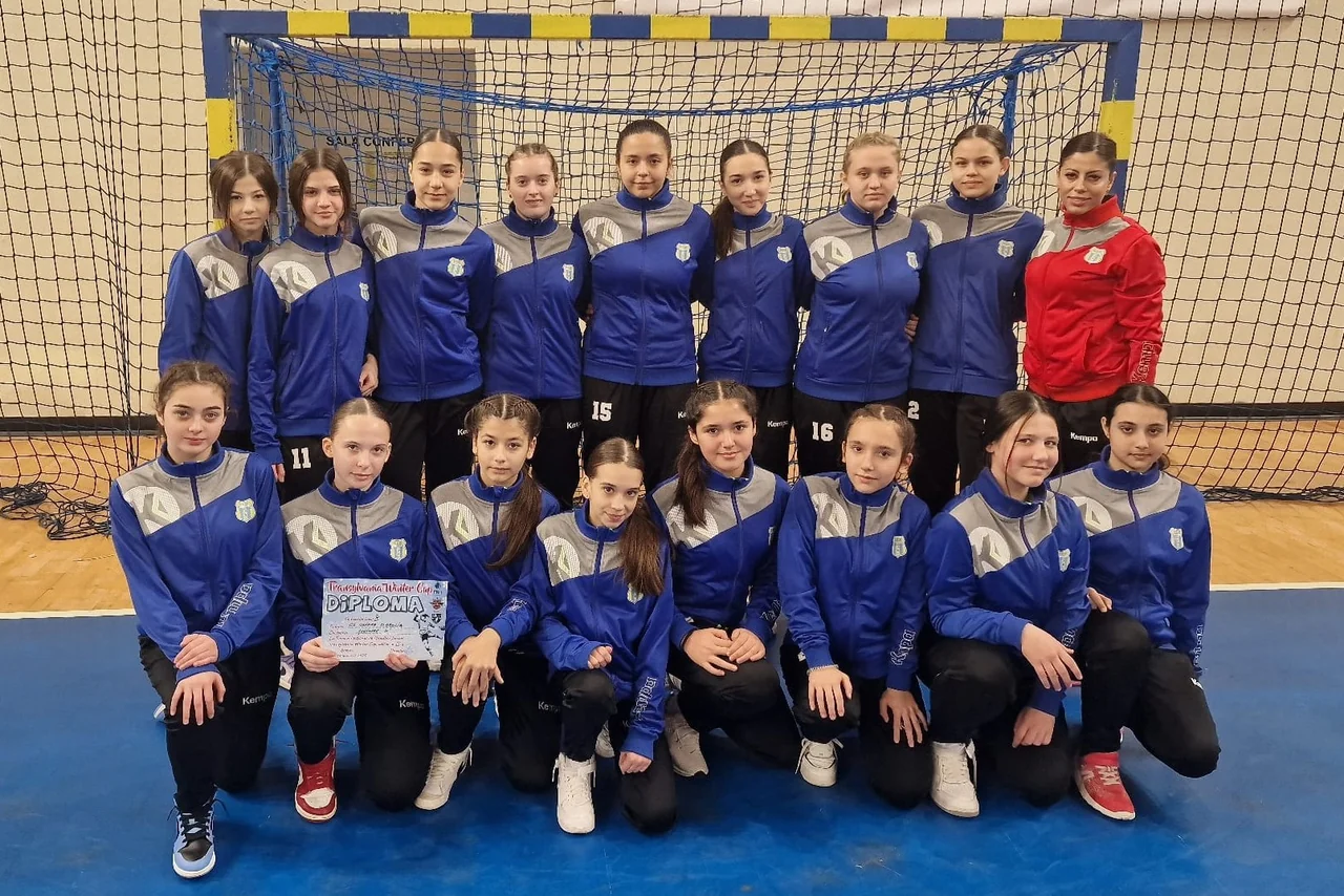 Echipa de junioare 3 în treninguri albastre, cu diploma de la Transylvania Winter Cup, în poză de grup cu antrenoarea.