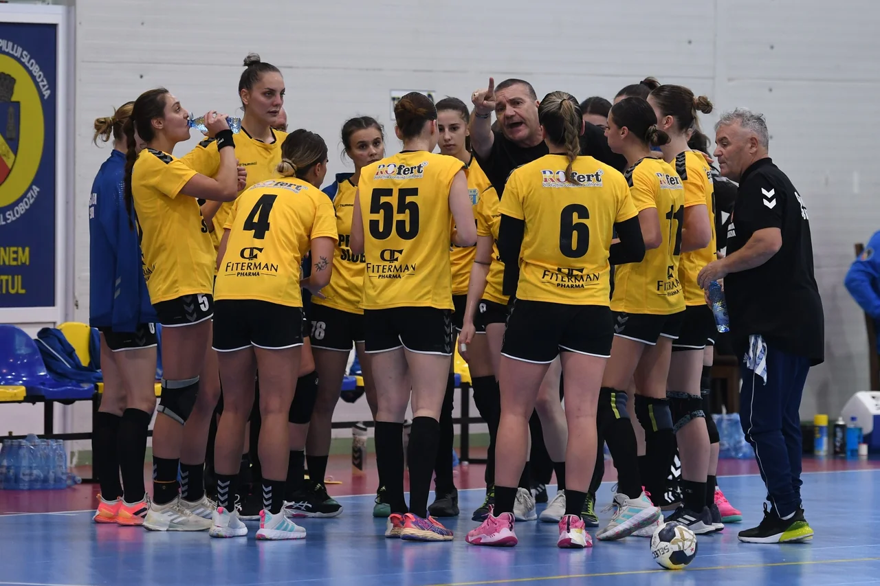 Jucătoarele echipei de handbal feminin a CSM Unirea Slobozia, în galben, ascultă indicațiile antrenorului într-o pauză a meciului.